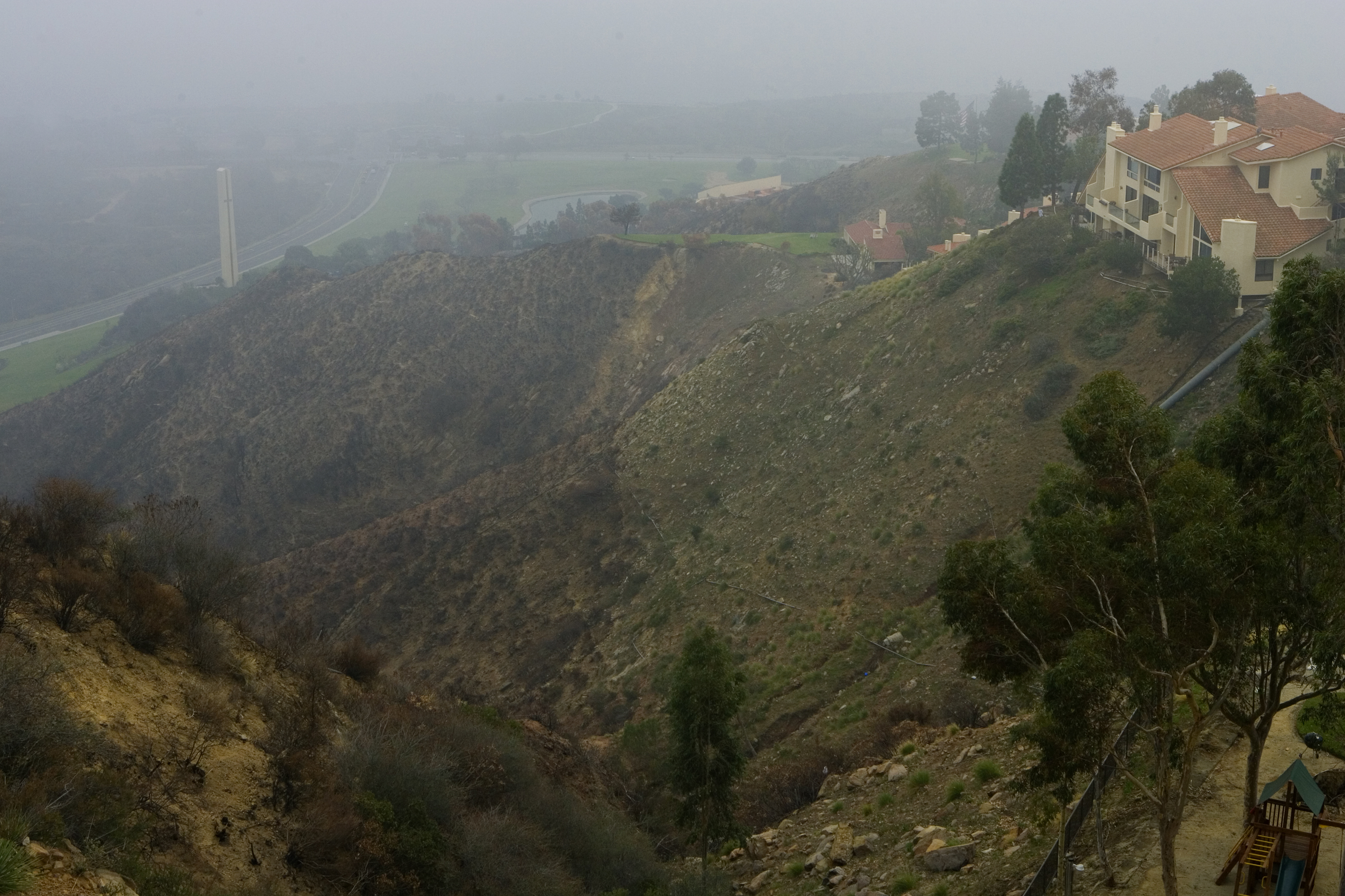 Homes with mitigated landscaping alongside burned vegetation in California, illustrating the value of defensible space